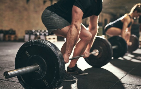 Heavy barbell with weights held by a man in the squat position